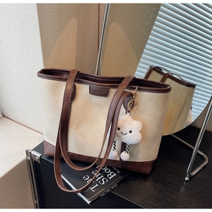 Detail of cream tote bag with dark brown straps and soft cloud pendant decoration