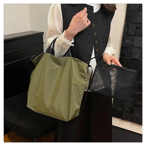 Detail of army green nylon tote bag with black mesh organizer pouch and wide shoulder strap