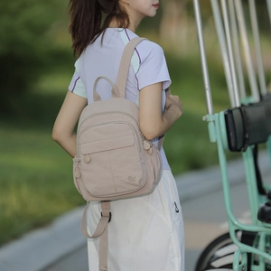 Gros plan d'un sac à dos en nylon imperméable beige montrant les détails des zips