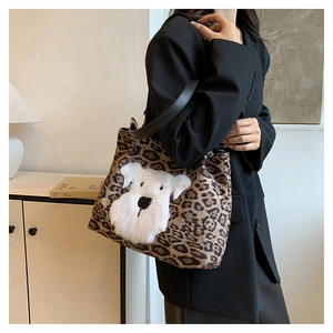 Detail view of leopard print tote bag with white fluffy dog patch and black leather straps