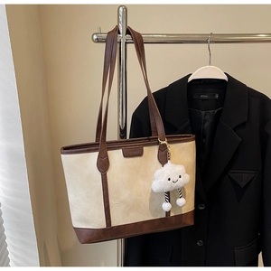 Detail of retro leather tote bag with brown straps and plush smiley face charm