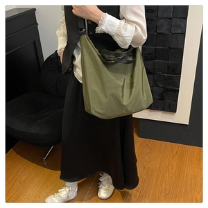 Close-up of olive green waterproof nylon tote bag carried by a model in a stylish room