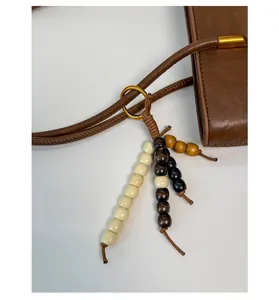 Close-up of bohemian wood bead charm with gold metal ring on a brown leather tote bag