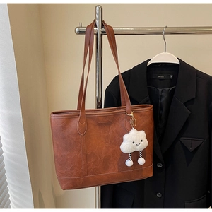 Close-up of retro brown faux leather tote bag featuring a cute white cloud plush charm