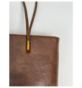 Detailed close-up of reinforced handle stitching and vintage brown leather texture