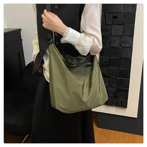 Olive green waterproof nylon tote bag with adjustable black strap worn as a crossbody