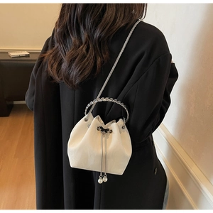 Détail du sac seau beige avec fermoir papillon en métal et pampilles en perles