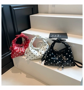 Detailed row of three polka dot handbags in red, white and black colors on steps
