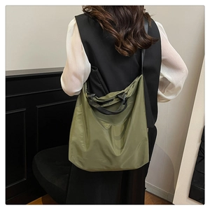 Army green nylon tote bag with black straps worn by model for a casual styling look