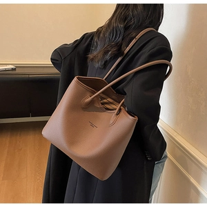 Détail d'un sac cabas en cuir marron avec texture de litchi porté à l'épaule