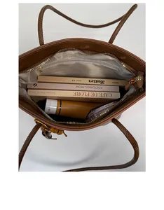Top view of spacious interior of brown tote bag with books and cosmetics inside
