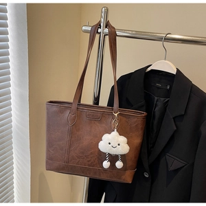 Close-up of vintage brown tote bag with leather texture and plush cloud keychain