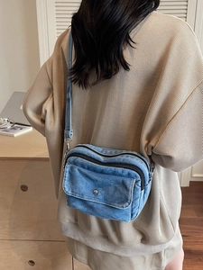 Minimalist blue denim crossbody bag with double zipper pockets and silver buckle detail