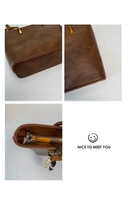 Detail view of vintage brown leather tote featuring oil wax texture and gold hardware