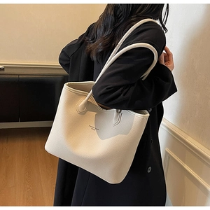 Modèle portant un grand sac cabas crème en cuir avec des bandoulières minimalistes