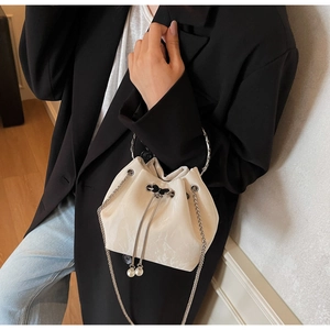 Détail du sac seau crème avec texture marbrée, poignée anneau argenté et cordons perle