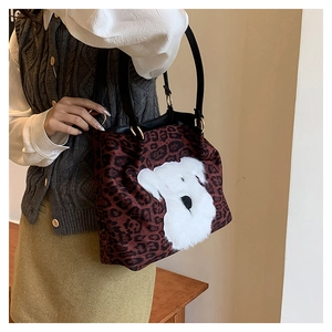 Detailed view of leopard print tote bag with plush animal patch and leather shoulder strap
