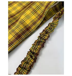 Detail of yellow plaid tote bag featuring a creative scrunchie-style pleated strap design