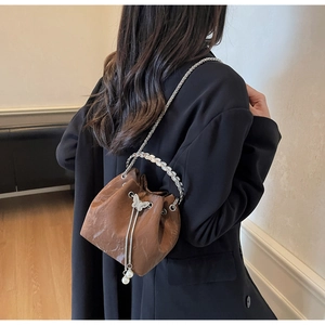 Détails du sac seau marron avec boucle papillon, gland perlé et poignée en forme de feuille