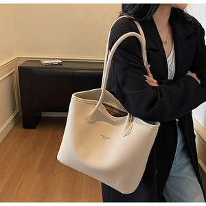 Vue latérale du grand sac cabas en cuir grainé beige avec doubles anses de transport