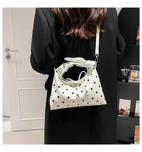 Detailed view of polka dot dumpling bag with knotted handle and detachable strap
