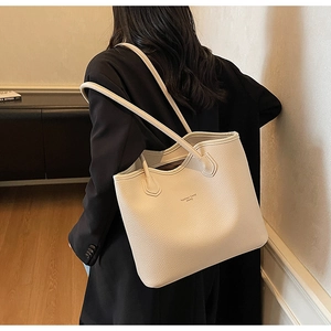 Modèle portant un grand sac cabas beige avec texture grainée pour le bureau