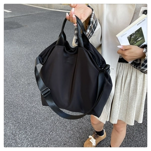 Macro shot of large black nylon tote bag featuring wide shoulder straps and matte finish