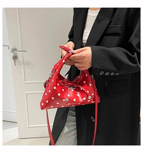 Detail of red polka dot crossbody bag with leather bow and silver sphere charm
