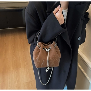 Détail d'un sac seau en cuir plissé marron avec fermoir papillon et breloques perles