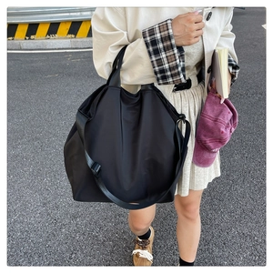 Outdoor street shot of large black waterproof nylon tote bag with adjustable shoulder strap