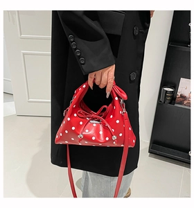 Close-up of red polka dot dumpling bag with leather bow and metallic bead details