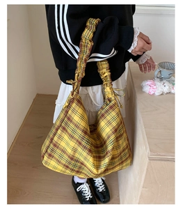 Detailed view of yellow plaid tote bag with stylish pleated strap and hobo design