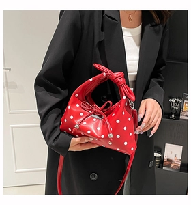 Close-up of red and white polka dot handbag featuring a decorative bow handle design