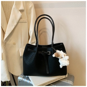 Détail du sac cabas tressé noir avec boucle de sangle et breloque agneau blanc en peluche