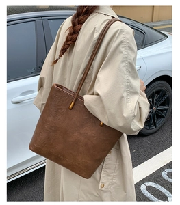 Detail of a brown leather tote bag showing fine texture and golden metal strap accents