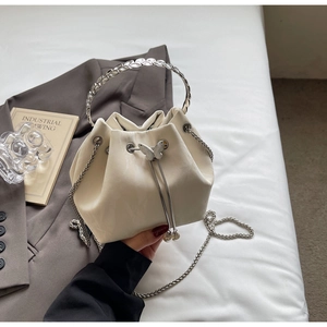 Détail du sac seau blanc cassé avec poignée en métal en forme de feuille et charme papillon