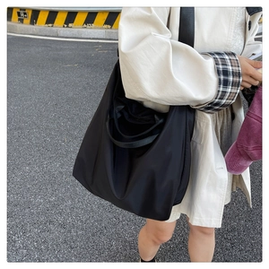 Detail of the wide shoulder strap on a black waterproof nylon tote bag for travel