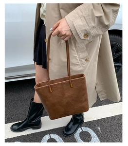 Detail of dark brown leather tote bag with elegant gold metal hardware and long handles