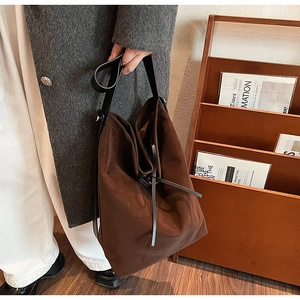 Detail of dark brown bucket bag with leather strap shown in a warm lifestyle setting