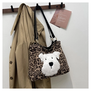 Close-up of leopard print tote bag with plush dog patch and leather shoulder strap