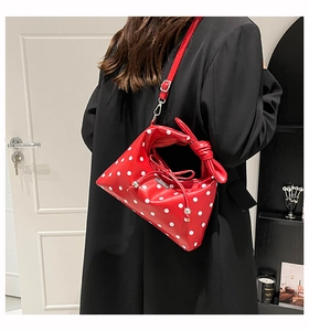 Detail of red polka dot crossbody bag with bow knot handle and drawstring closure