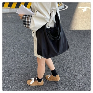 Detailed outdoor view of large black waterproof nylon tote bag worn by a model
