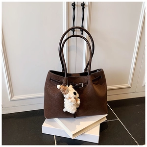 Détail du sac cabas marron avec texture tissée, doubles poignées et breloque chien peluche