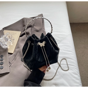 Détail du sac seau noir texturé avec breloque papillon et poignée en strass brillants