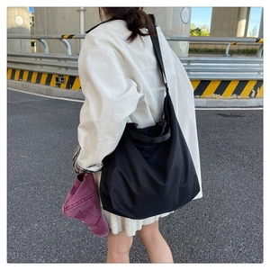 Outdoor street view showing the large capacity black waterproof nylon tote bag in use
