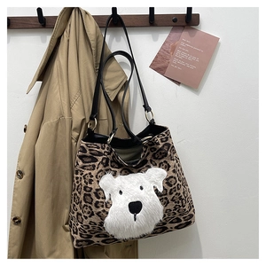 Detail of leopard print tote bag with plush cartoon dog embroidery and leather straps