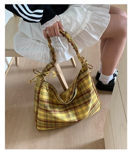 Detail of vintage plaid tote bag featuring pleated handles and bow tie decorations