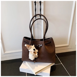 Détail du sac cabas tressé marron foncé avec boucle en cuir et charm chiot en peluche