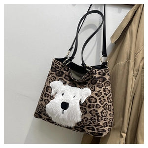 Detail of leopard print tote bag with plush puppy patch and black leather handles