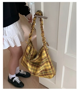 Detail of yellow plaid tote bag featuring a unique scrunched shoulder strap design